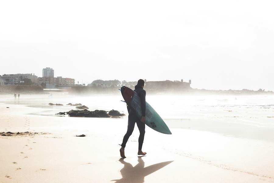 Man walking down the beach to surf Matisinhos