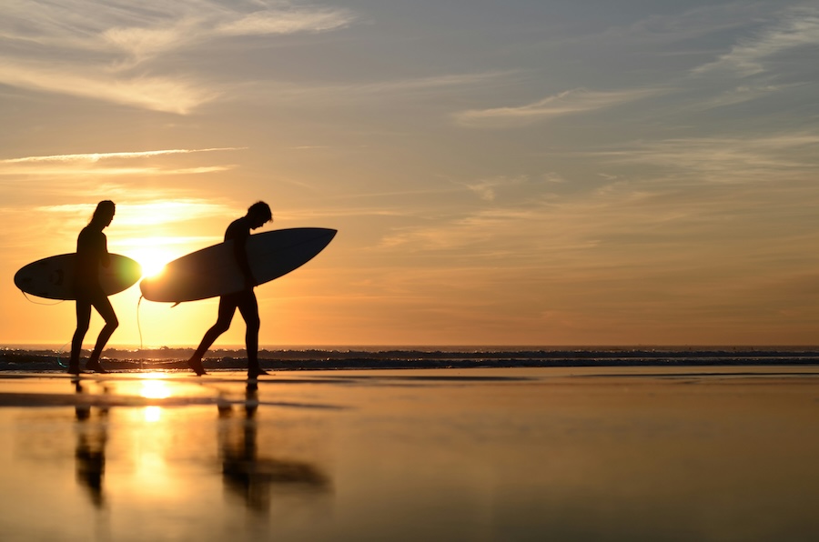 Surfers walking at sunset on Maceda beach